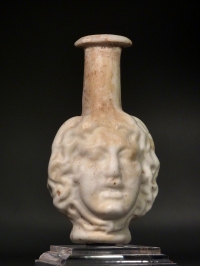 Roman molded opaque white glass Medusa Janus head flask.