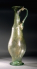 Roman light-green glass elongated jug with one handle, molded body with diagonal ribbing.