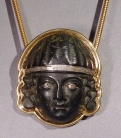 Early Roman bronze applique head of a woman with silver eyes and diadem, set in modern 18k gold setting.